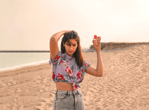 woman uses Calypso scalp protection spray on a beach